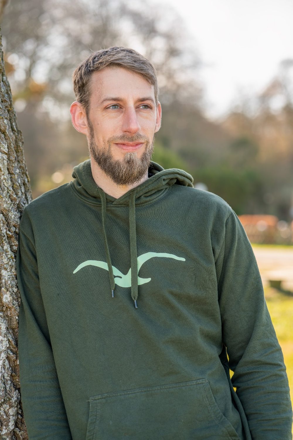 Lennart Hübner im grünen Hoodie, an einen Baum gelehnt